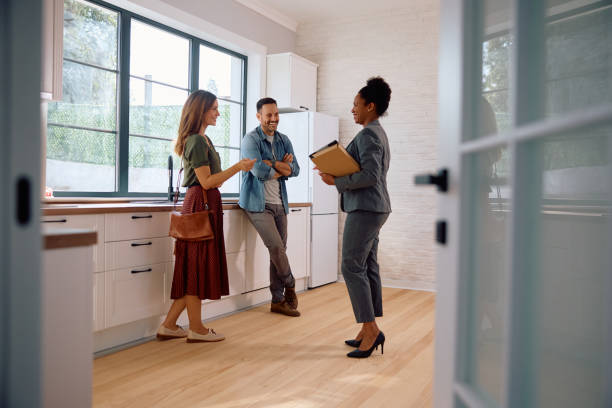 Housing advisor showing a couple around a bright modern apartment during a viewing